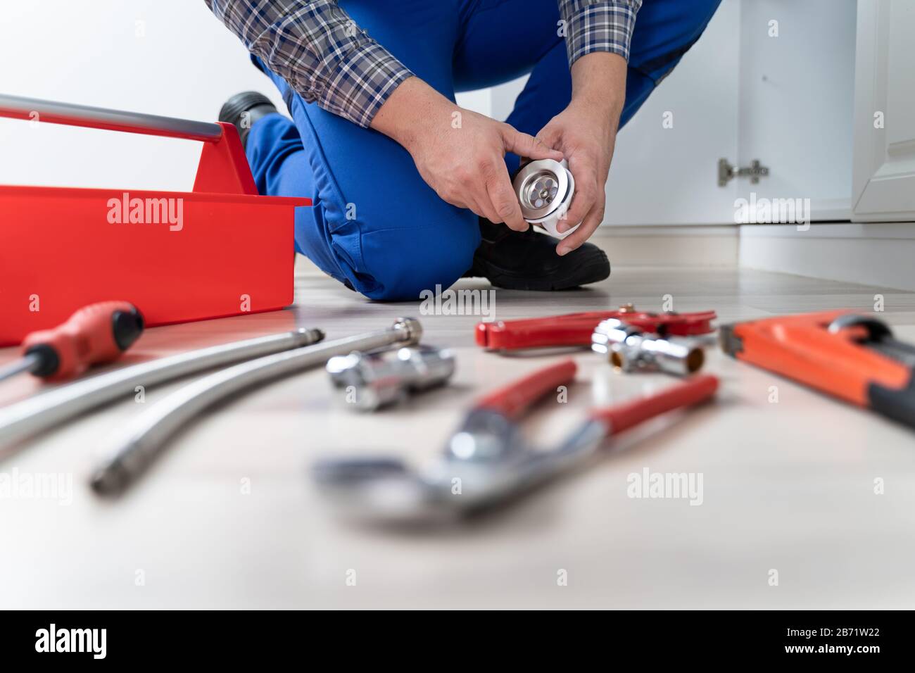 Male Plumber In Overall Fixing Kitchen Sink Pipe Stock Photo
