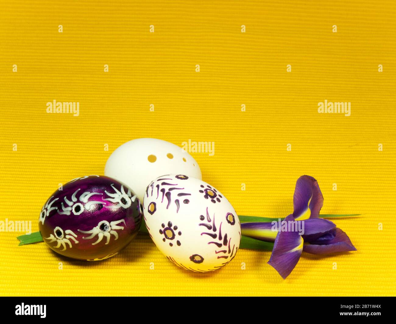 Three easter eggs and iris on yellow Stock Photo