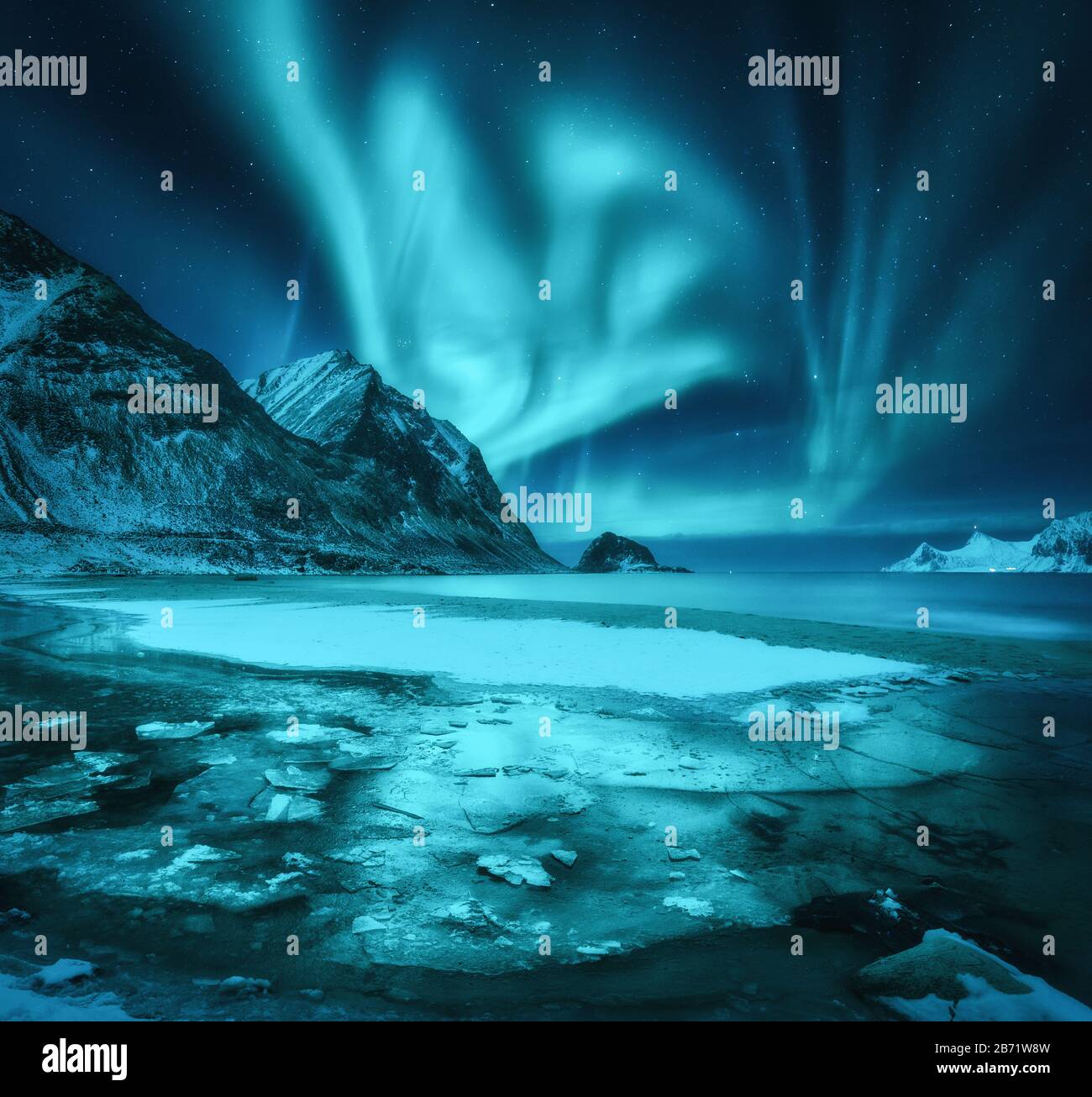 Northern lights over snowy mountains, frozen sea coast Stock Photo