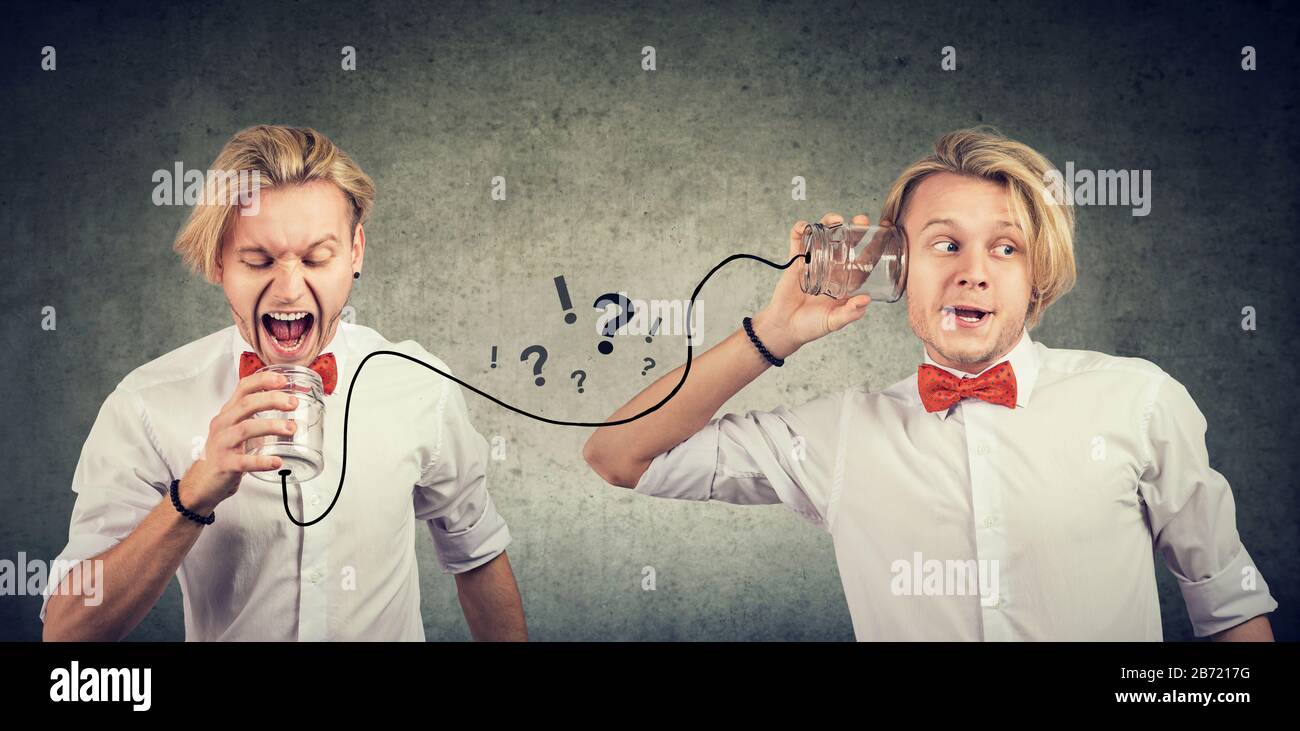Curious young businessman with questions listening to angry self inner voice Stock Photo