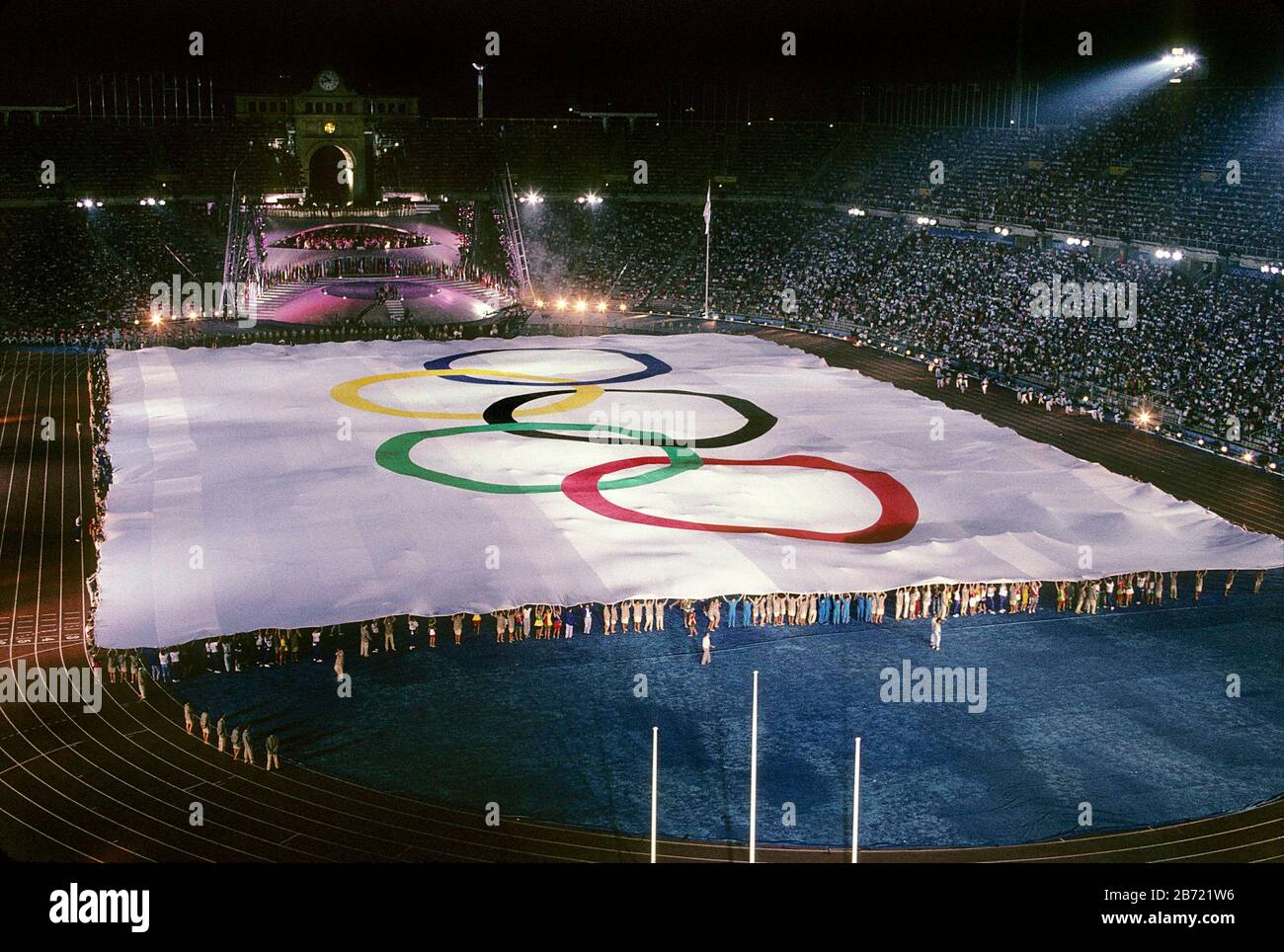 Barcelona, Spain, 1992: Hundreds of people hold edges of huge Olympic flag on the field at Montjuic Stadium during opening ceremonies of the Olympic Summer Games.   ©Bob Daemmrich Stock Photo