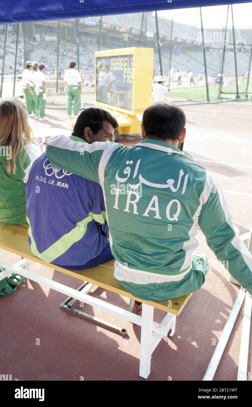 Barcelona, Spain: Male athletes from Iran (left) and Iraq sit together and talk during field events at track stadium during 1992 Summer Olympics.    ©Bob Daemmrich / Stock Photo