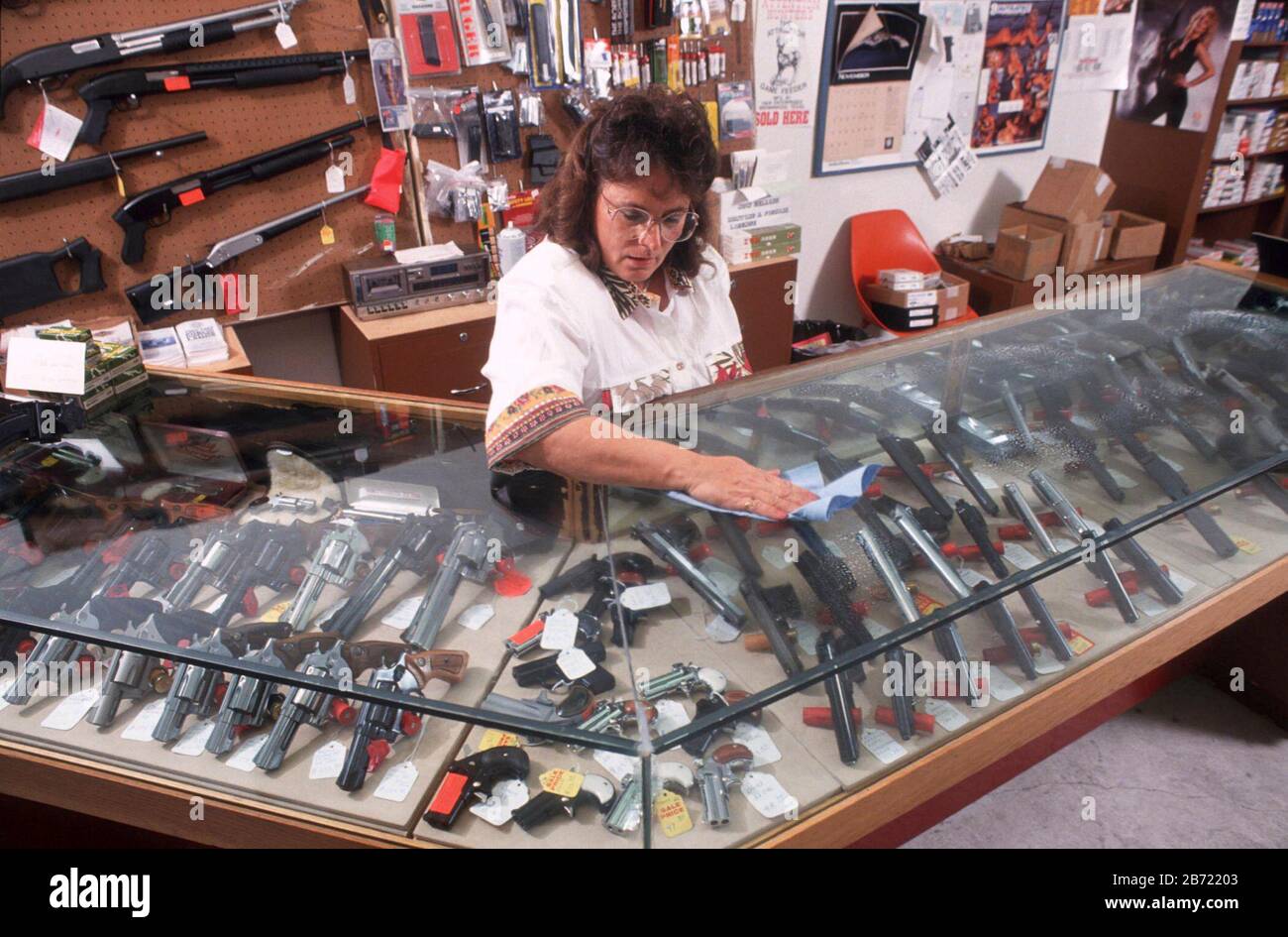 Austin, Texas USA: Female employee cleans glass case covering expensive guns on display at small firearms shop.   MR ©Bob Daemmrich Stock Photo