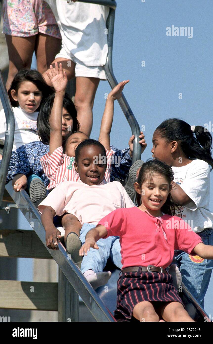 Austin Texas USA: Multi-racial group of children play on playground slide on sunny day. ©Bob Daemmrich Stock Photo