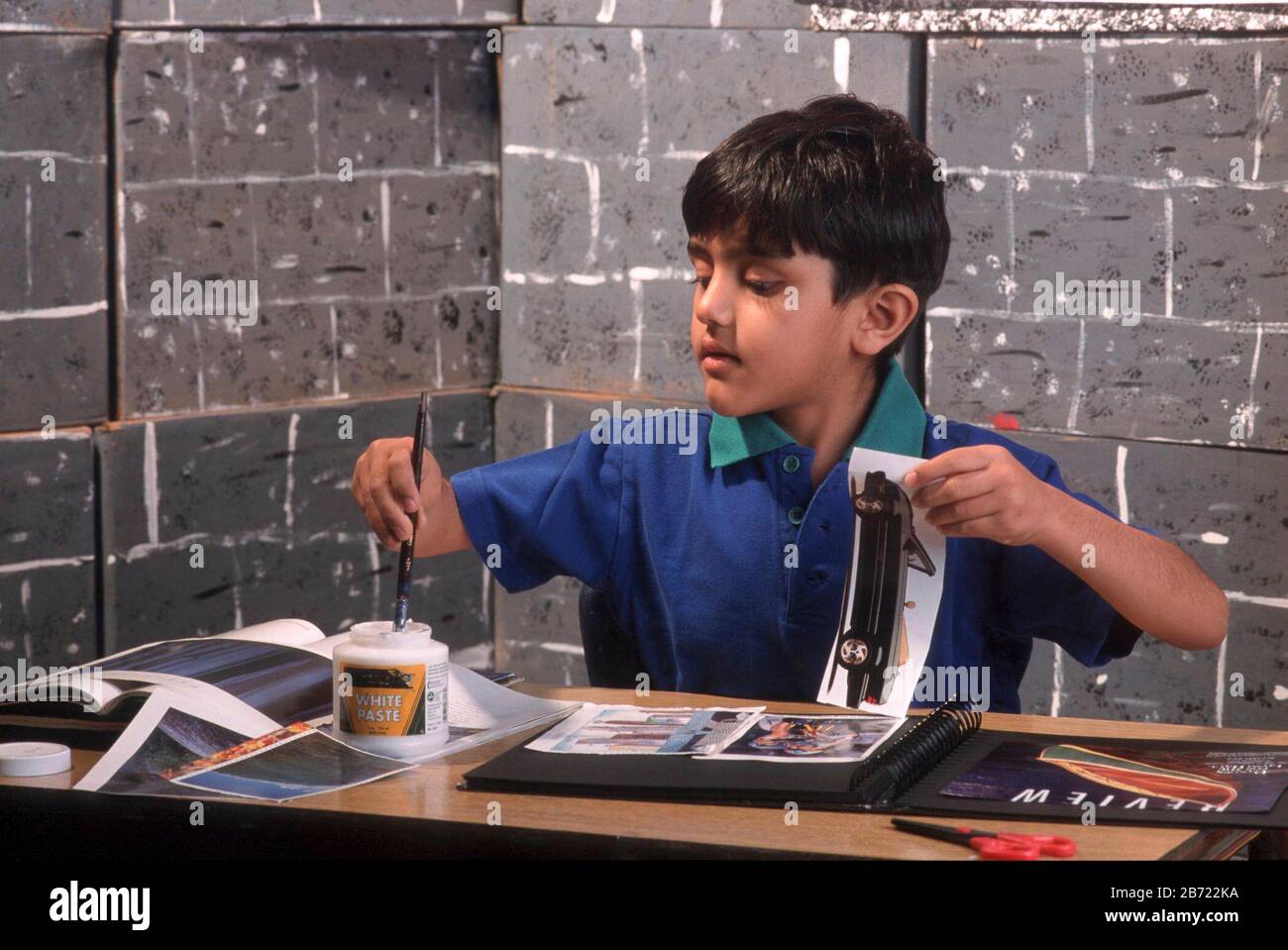 Austin, Texas USA:  Indian-American boy uses glue for pasting pictures in scrapbook for kindergarten project. ©Bob Daemmrich Stock Photo