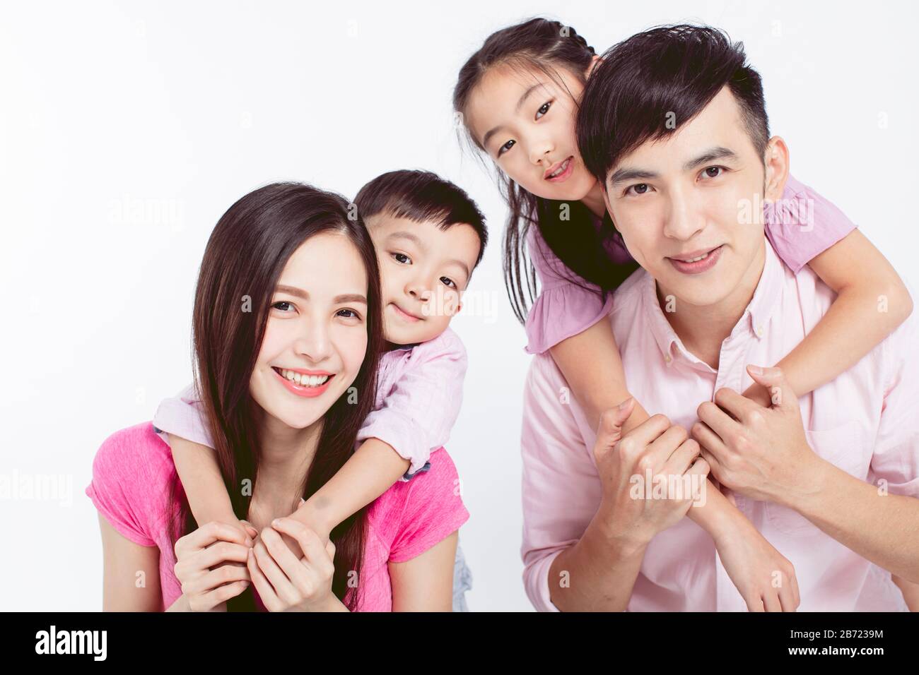 Young parents piggybacking their two kids isolated on white Stock Photo