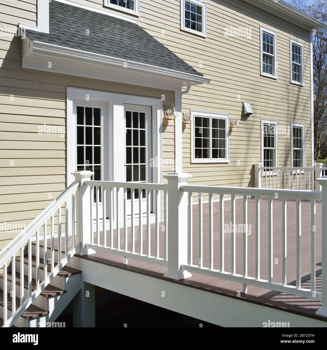 Garden deck and french doors, detail. Champagne house siding, red brown boards, white railings and frame. Stock Photo