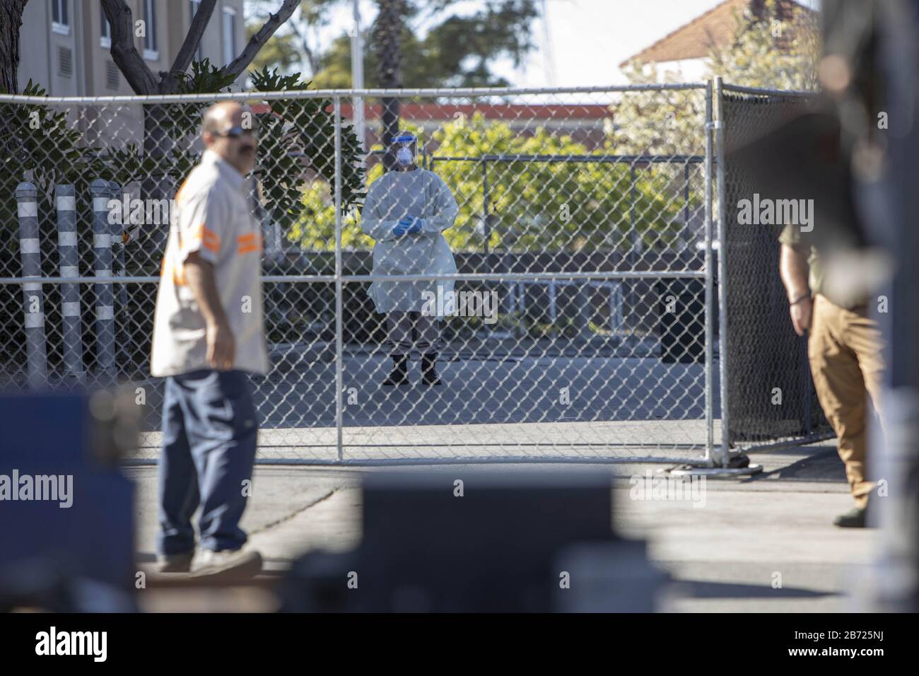 San Carlos, United States. 12th Mar, 2020. An unidentified health worker looks on from behind a chain linked fence surrounding the Fairfield Inn, a hotel purchased by the State of California to be used as a quarantine facility for CCOVID-19 patients, as a delivery driver gets directions from a US Marshal that is guarding the facility in San Carlos, California on Thursday, March 12, 2020. Photo by Peter DaSilva/UPI Credit: UPI/Alamy Live News Stock Photo