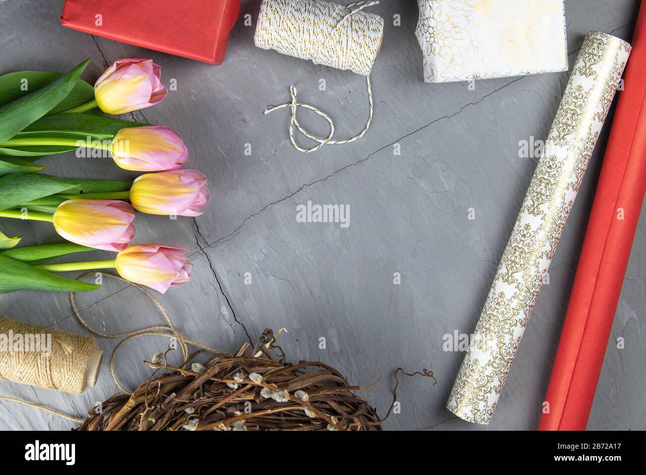 Preparing for the packaging of gifts, on the table laid out red and white wrapping paper