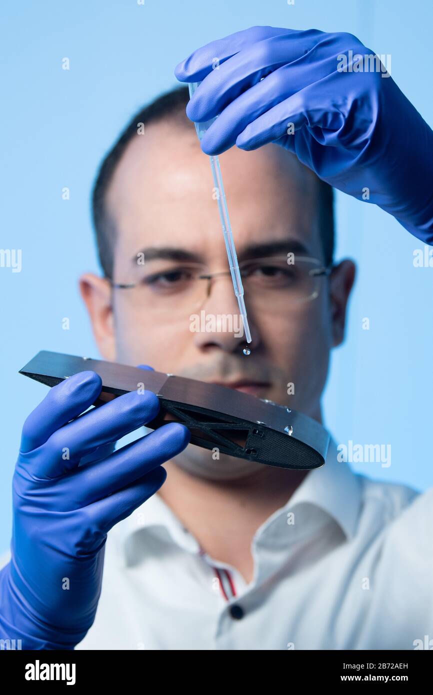 Dresden, Germany. 11th Mar, 2020. Sabri Alamri, research associate at the Fraunhofer Institute for Material and Beam Technology IWS, sprays distilled water with a pipette onto the water-repellent structured surface of a NACA profile, a miniaturized and realistic wing of an airplane. The structure of the aircraft surface is processed with a laser in such a way that ice adheres less well to prevent it from freezing on the wings - the so-called anti-icing effect. Credit: Sebastian Kahnert/dpa-Zentralbild/dpa/Alamy Live News Stock Photo