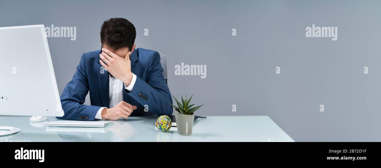 Man Suffering From Headache Working In Office Stock Photo