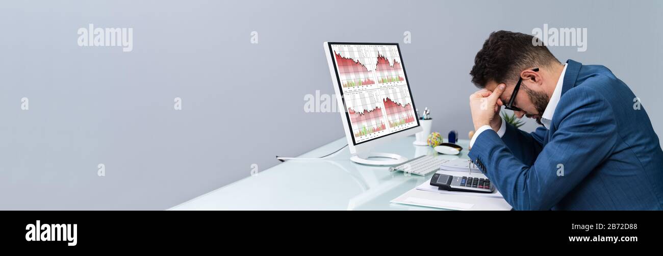 Despairing Businessman Faced With Financial Losses Looking On Graphs Dropping Into The Red Stock Photo