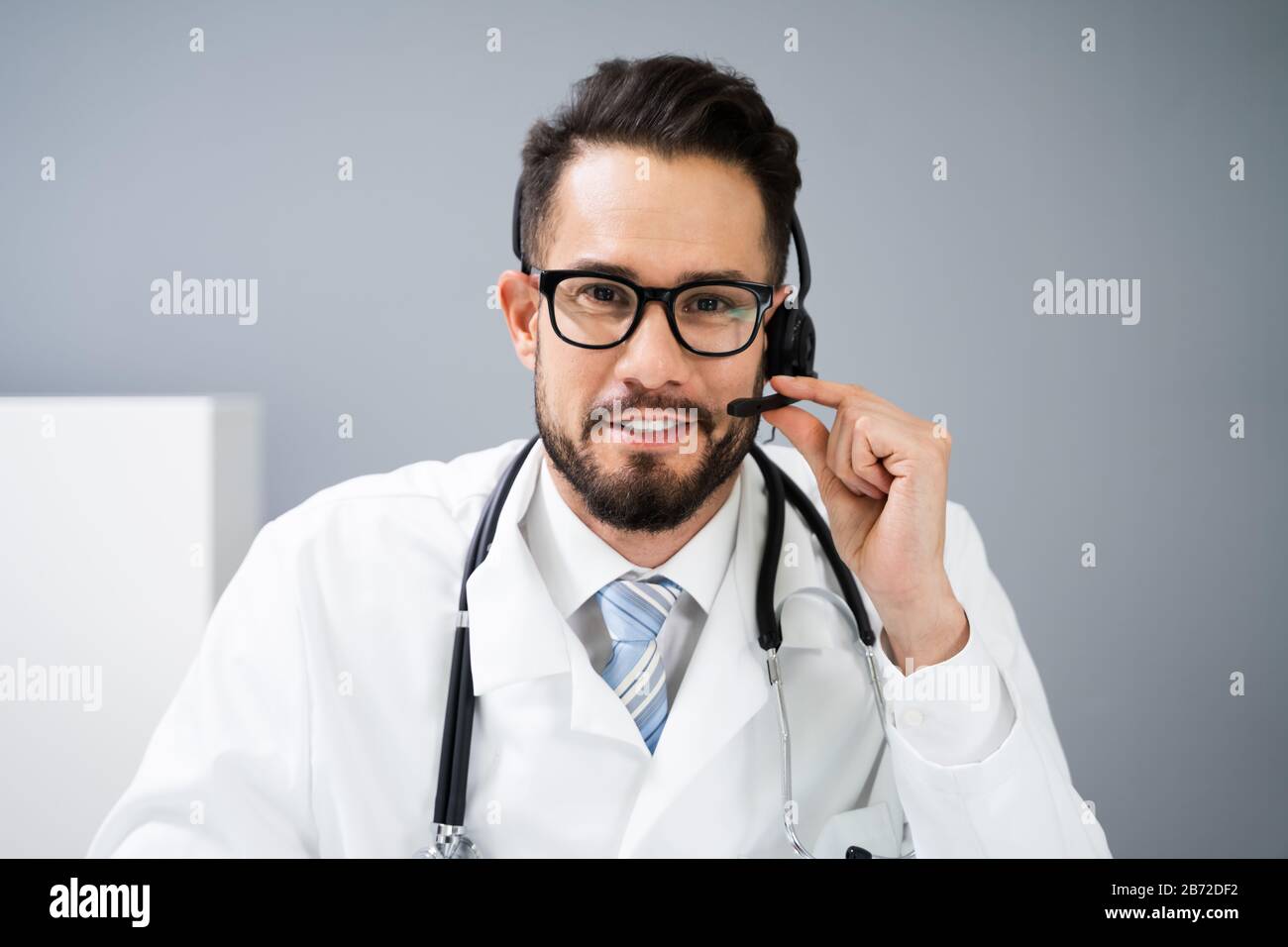 Close-up Portrait Of Confident Receptionist Using Headset In Hospital Stock Photo