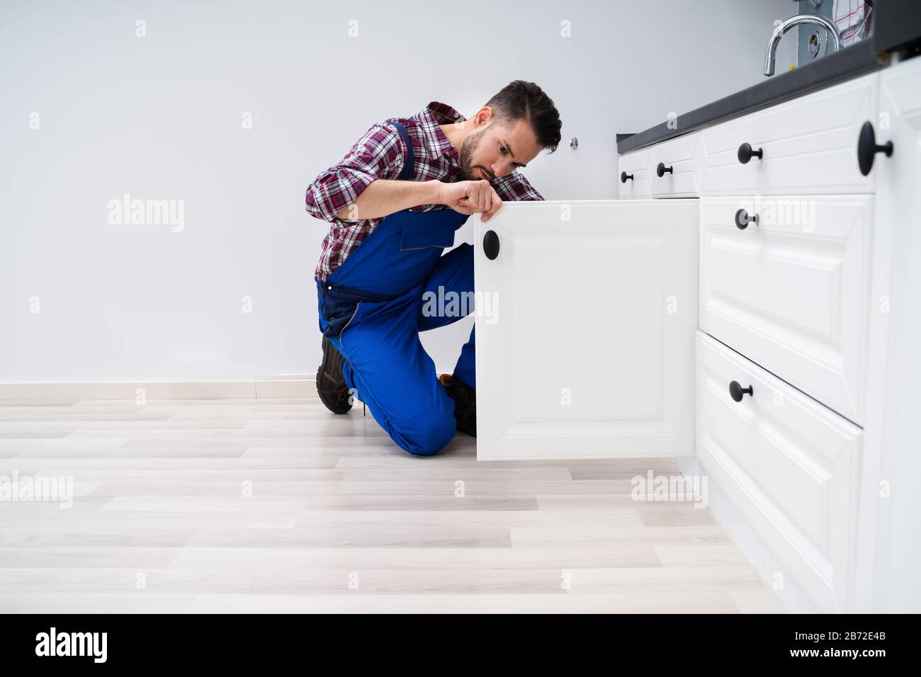 Young Handyman Fixing Sink Door In Kitchen Stock Photo - Alamy