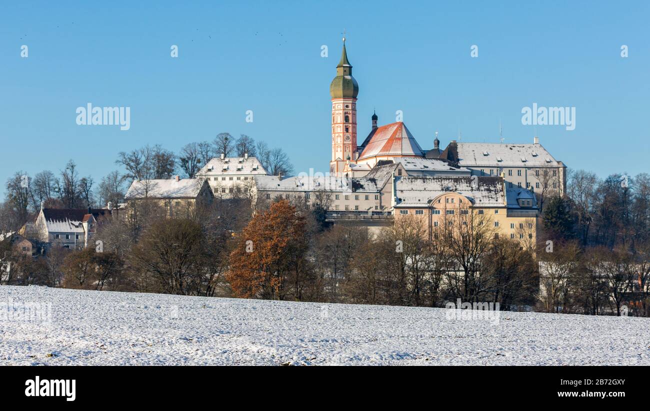 Panorama of Kloster Andechs during winter. A snow covered field and trees in the foreground. Benedictine monastery / abbey, baroque architecture. Stock Photo