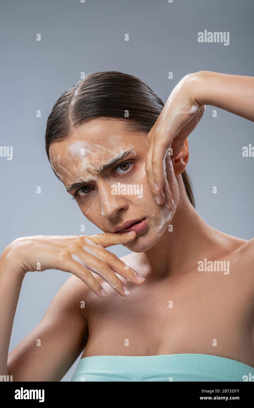 Young pretty lady scrubbing her face with soap Stock Photo