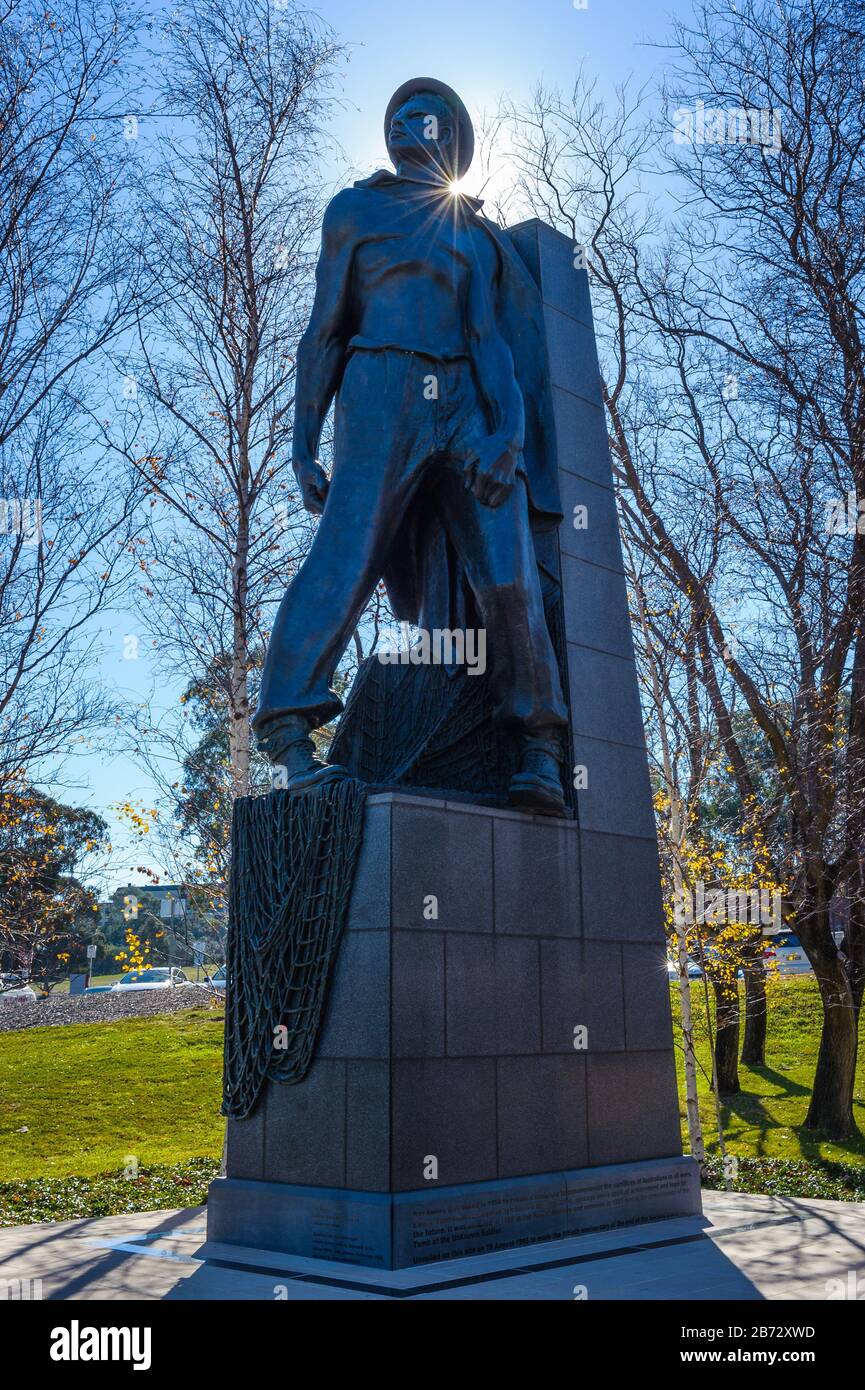 Upright, bronze lone soldier statue, with sun spike over his left shoulder commemorating the contribution of all Australian soldiers. Stock Photo