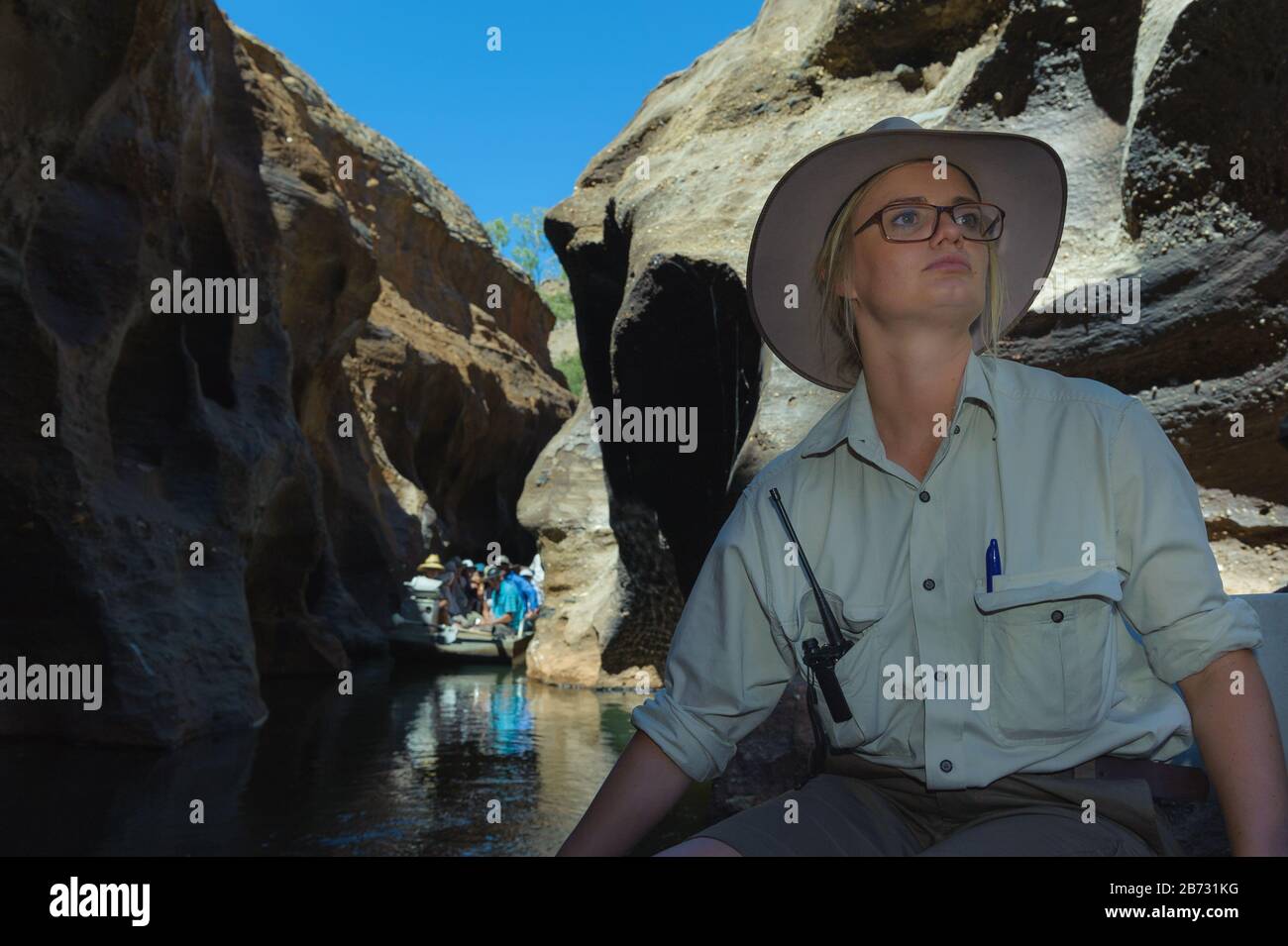 Cobbold Gorge female tour guide, steers her tour boat along the narrow gorge walls as another tour guide boat approaches from behind. Stock Photo