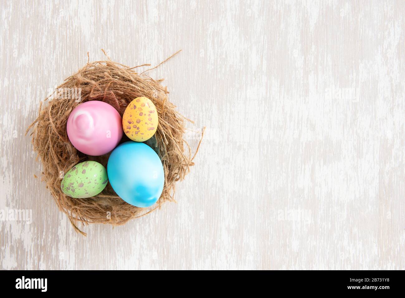 Easter eggs in nest on simple white wash wood tabletop - flat lay ...