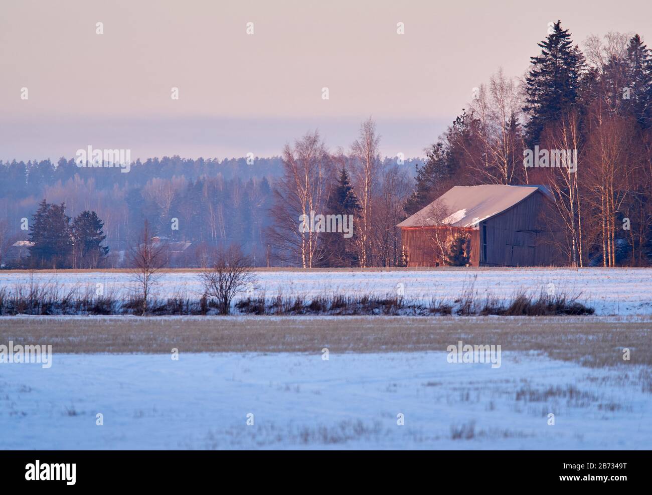 Countryside scenery with old barn and snow on the field. Very calm and peaceful atmosphere of cold day in winter. Stock Photo