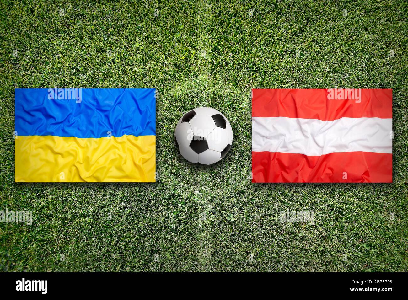 Ukraine vs. Austria flags on green soccer field Stock Photo
