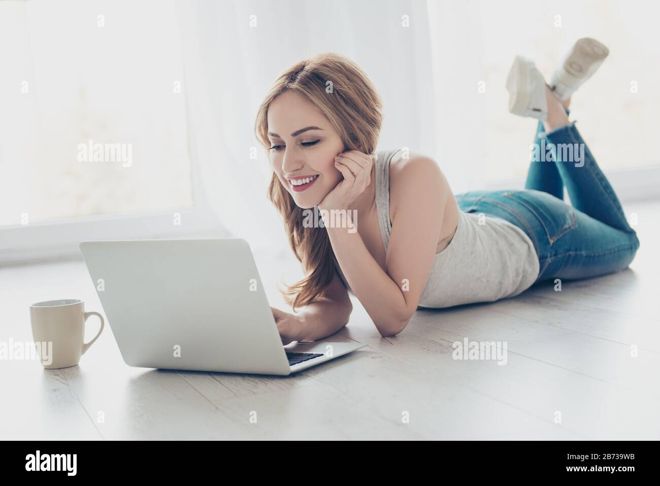 Pretty smiling cute girl lying on the floor and using laptop Stock ...
