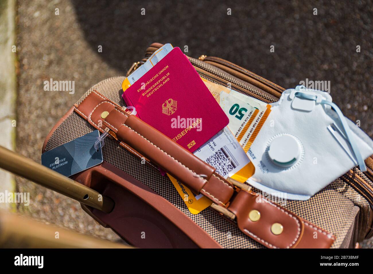 Munich, Germany - March 13th 2020: Air traveler business baggage with face mask for protection against the sars-cov-2 virus. Stock Photo