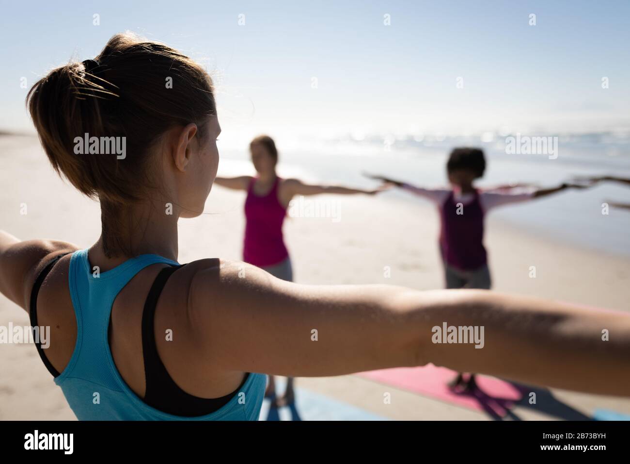Rear view of women stretching together at the beach Stock Photo