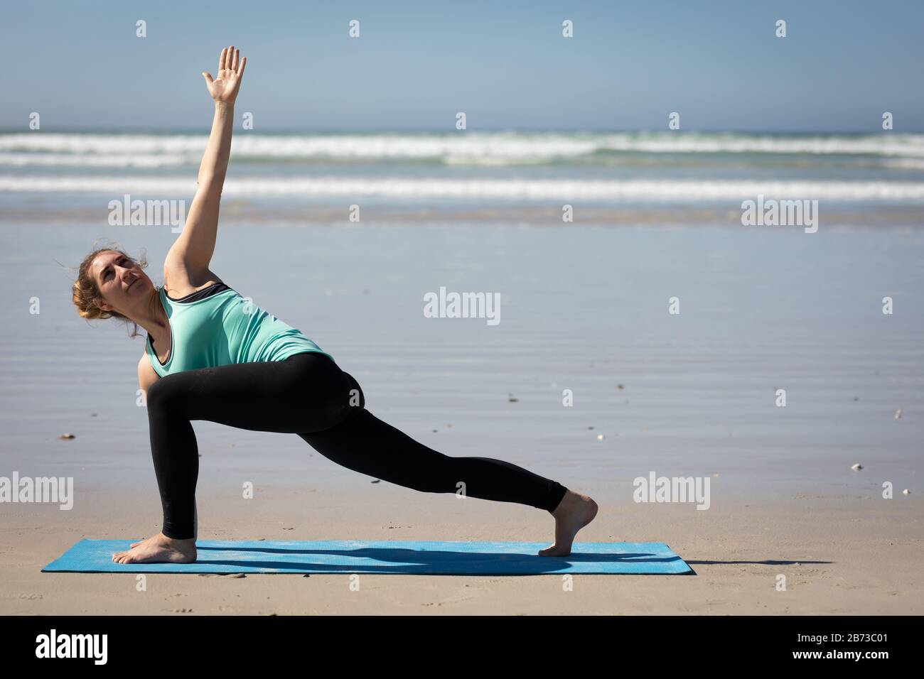 Side view of woman doing a yoga position at the beach Stock Photo