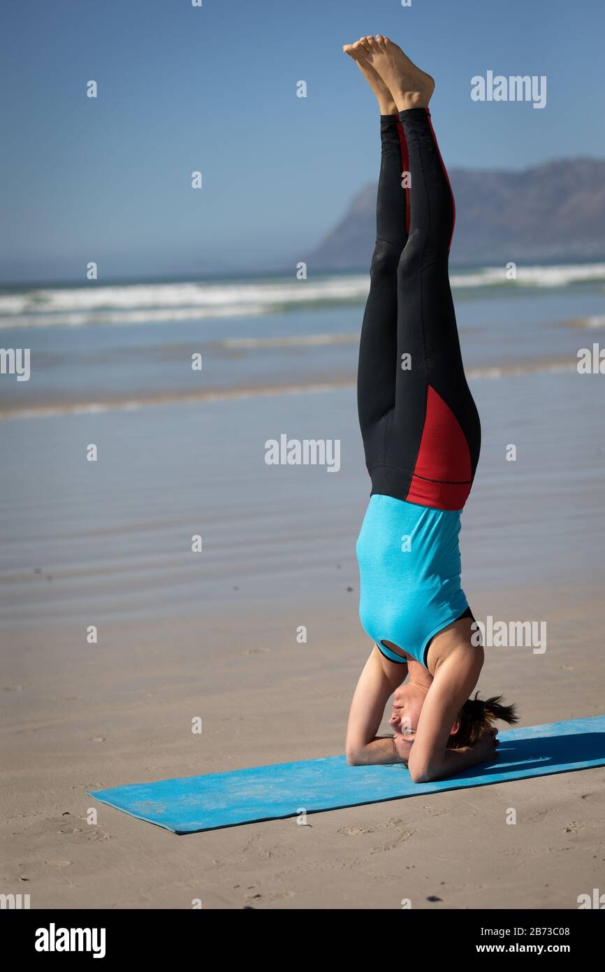 Side view of woman doing a yoga position at the beach Stock Photo