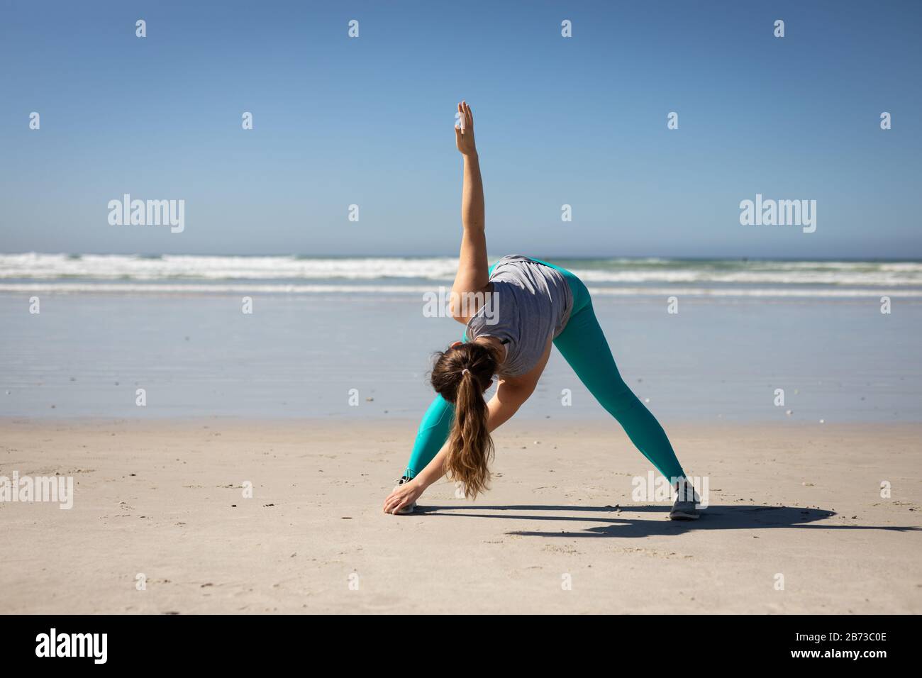 Front view of woman doing a yoga position at the beach Stock Photo