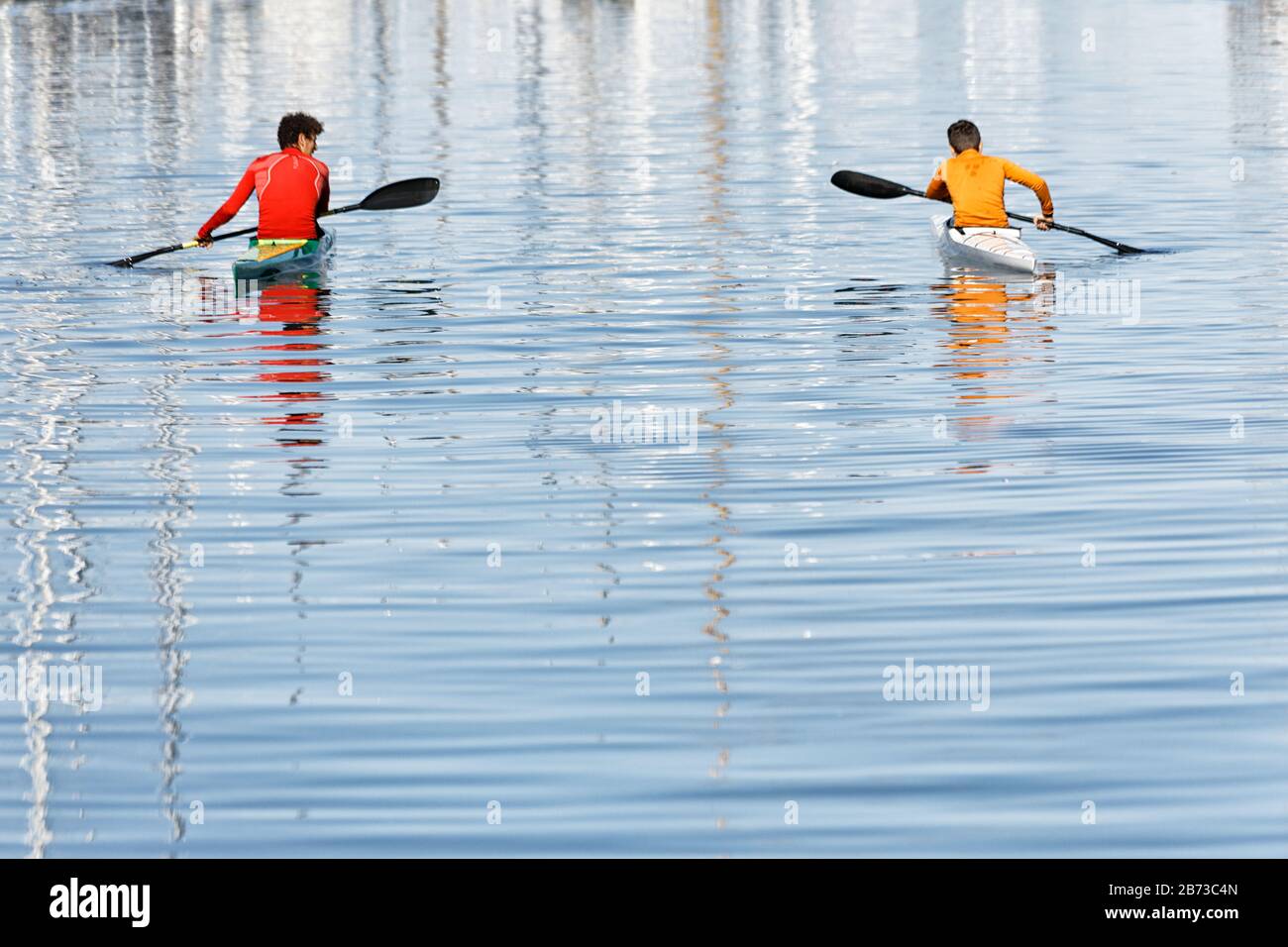 Red and yellow canoe rowers on silvery waters Stock Photo