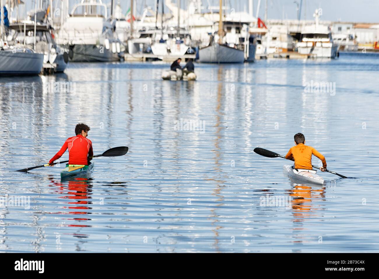 Red and yellow canoe rowers on silvery waters Stock Photo