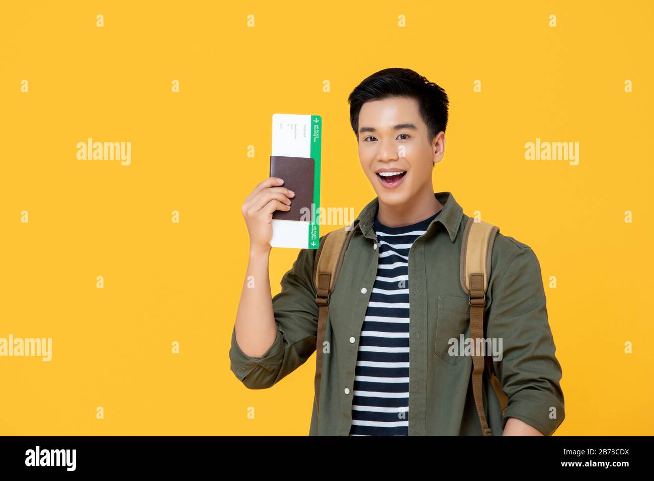 Young handsome Asian tourist man smiling and holding passport with boarding pass ready yo fly Stock Photo