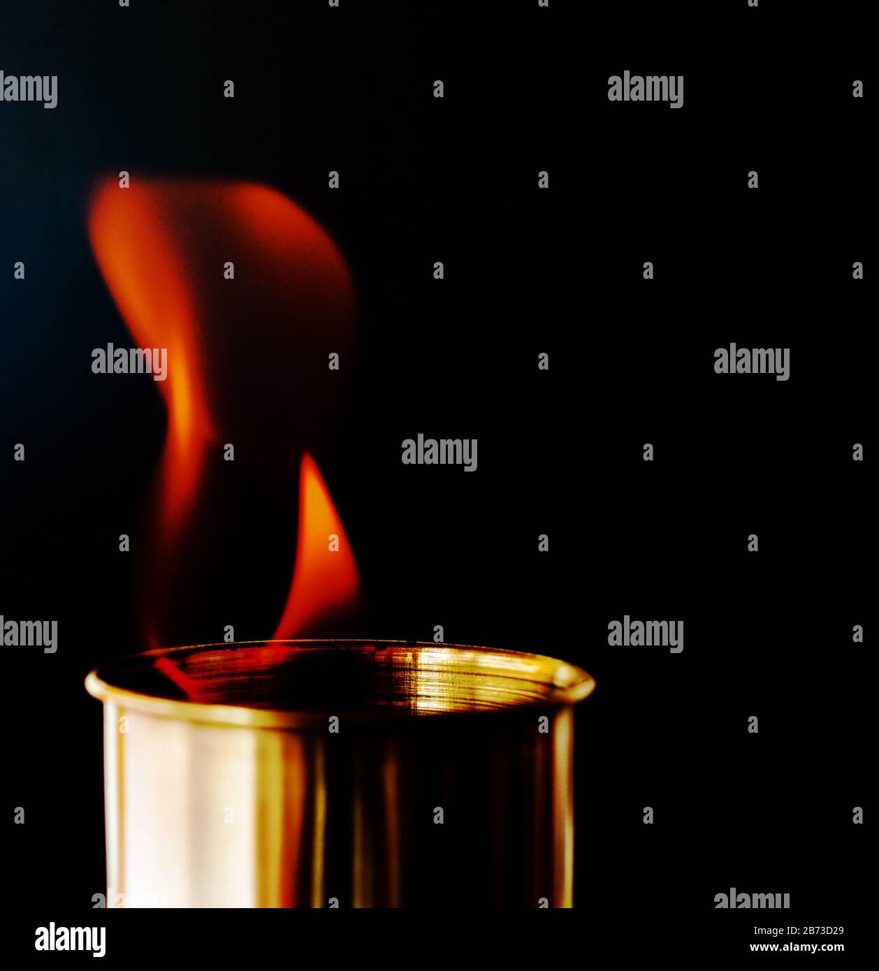 Flame, burning candle on a black background. Brass candle. Danger. Fire