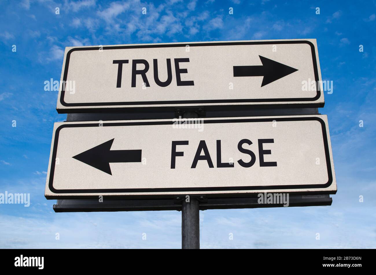 True vs false. White two street signs with arrow on metal pole with word. Directional road. Crossroads Road Sign, Two Arrow. Blue sky background. Two Stock Photo