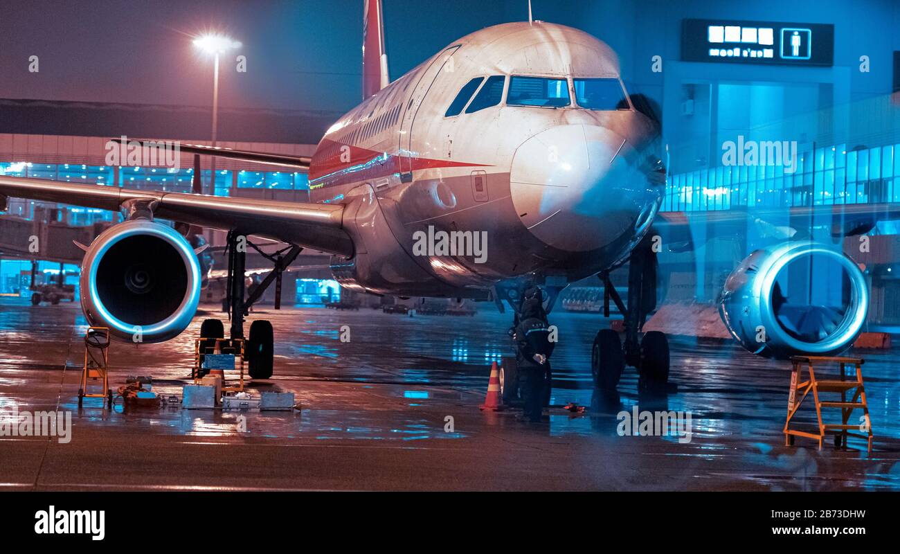 A passenger plane docked on the tarmac.  The huge plane can be seen through the window.  This was taken in the early hours of the morning. Stock Photo