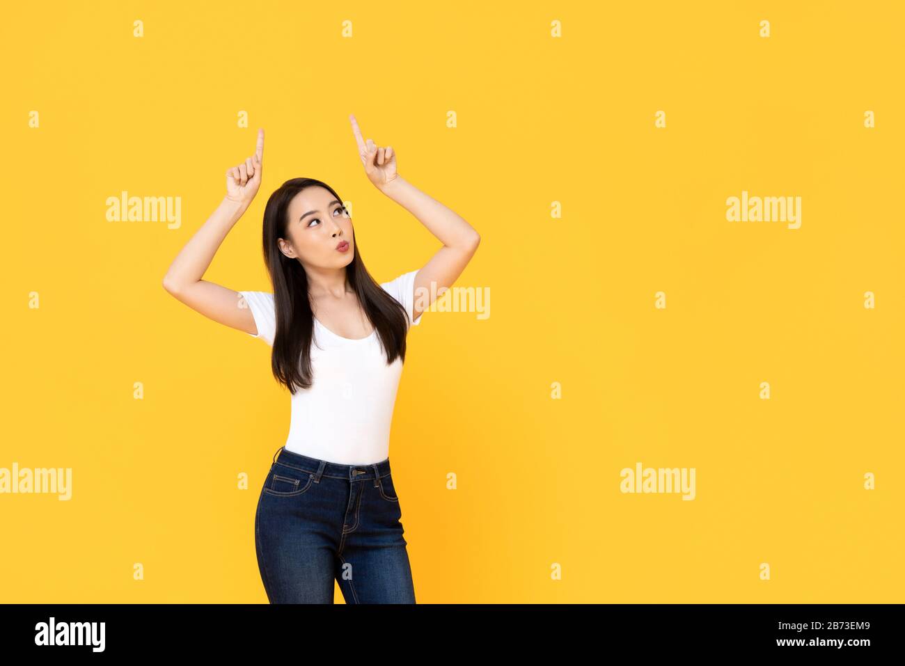 Young beautiful Asian woman pointing up with her two fingers while ...