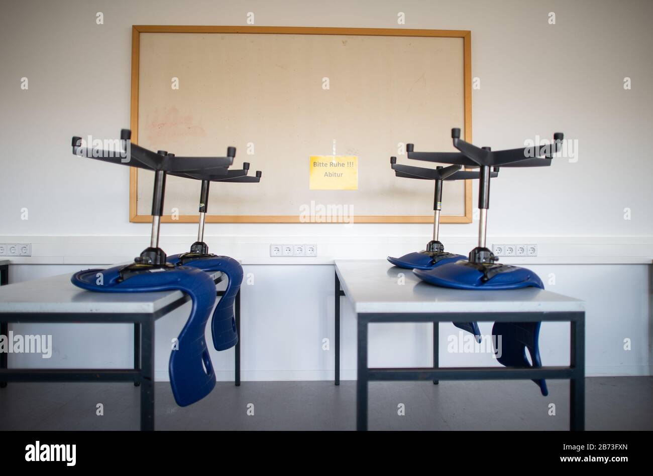 13 March 2020, North Rhine-Westphalia, Übach-Palenberg: Chairs stand on tables in an empty classroom in the Carolus-Magnus-Gymnasium, while on the wall there is a sign saying 'Please be quiet! Abitur' can be seen on the wall. In the district of Heinsberg the schools and kindergartens will remain closed for another week, perspectively even until the Easter holidays. Photo: Jonas Güttler/dpa Stock Photo