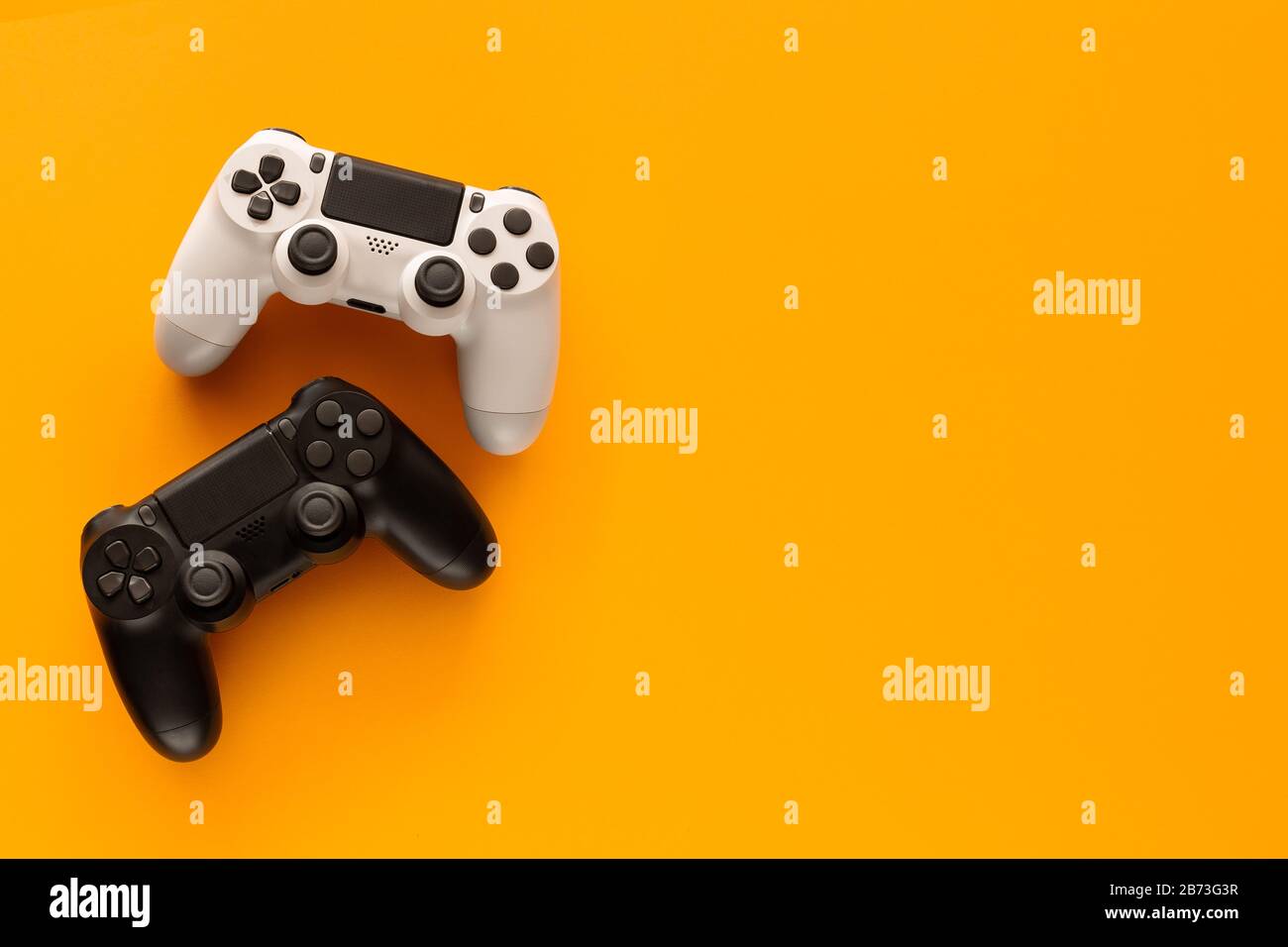 Stock photo of two gamepads on a yellow background and copy space on the right Stock Photo