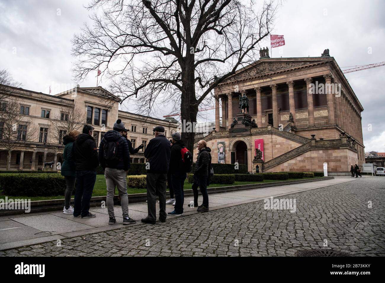 Berlin, Germany. 13th Mar, 2020. Passers-by stand in front of the National Gallery. Due to the coronavirus (COVID-19), the Stiftung Preußischer Kulturbesitz (Prussian Cultural Heritage Foundation) is closing all of its locations in Berlin from Saturday until further notice. All museums on the Museum Island are affected, as well as the Hamburger Bahnhof, the Museum Berggruen and the Museum of Photography. Credit: Paul Zinken/dpa/Alamy Live News Stock Photo