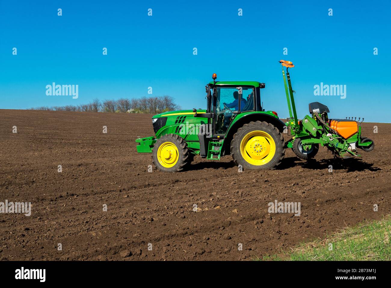 Young Farmer Sowing Crops At Field With Pneumatic Sowing Machine