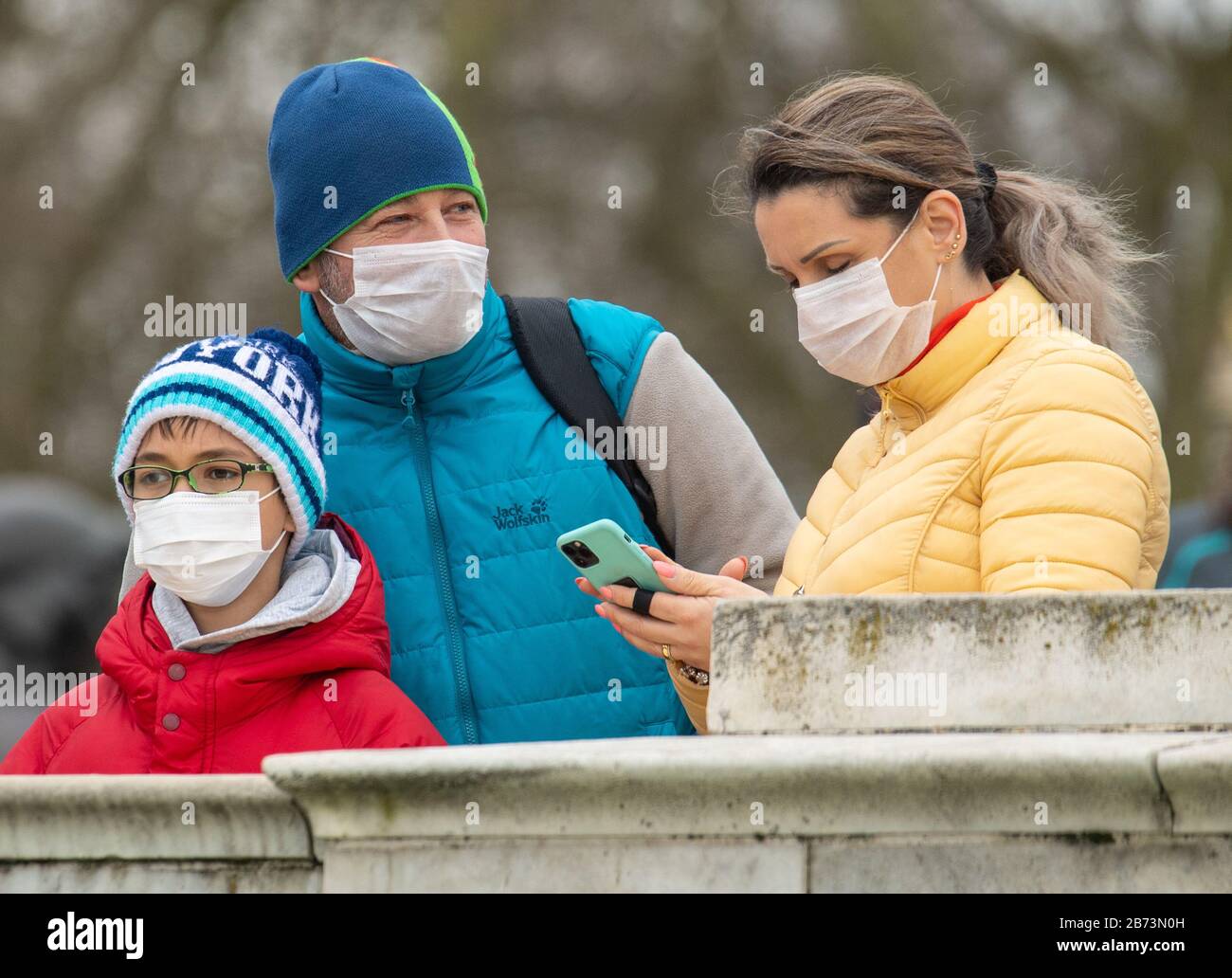 People wearing protective face masks watch the Changing of the Guard ceremony outside Buckingham Palace, London, the day after the Prime Minister said that Covid-19 'is the worst public health crisis for a generation', and the government's top scientist warned that up to 10,000 people in the UK are already infected. PA Photo. Picture date: Friday March 13, 2020. See PA story HEALTH Coronavirus. Photo credit should read: Dominic Lipinski/PA Wire Stock Photo