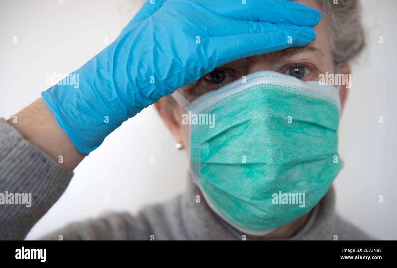 Older woman wearing protective surgical mask and surgical gloves (posed ...
