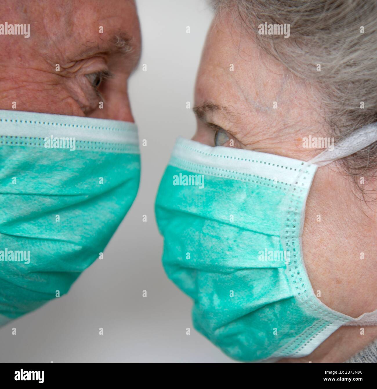Older male and female in close proximity wearing protective surgical masks (posed with models). Stock Photo