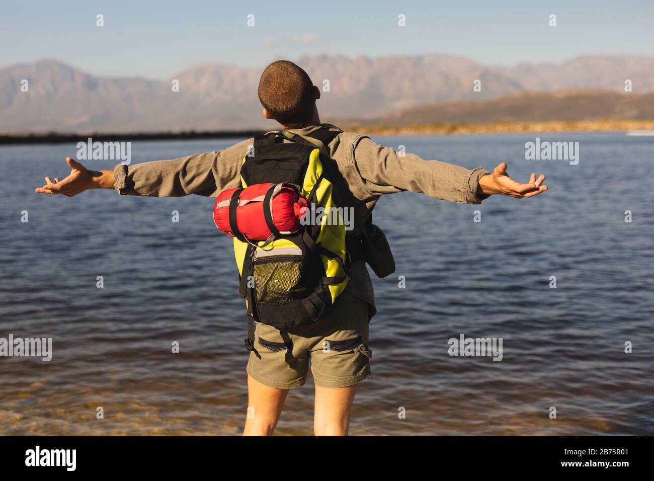 Rear view of man with backpack in front on a lake Stock Photo