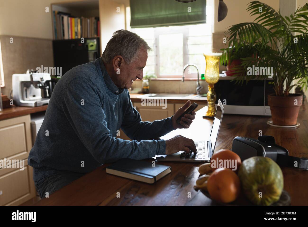 Senior man using laptop in his kitchen Stock Photo