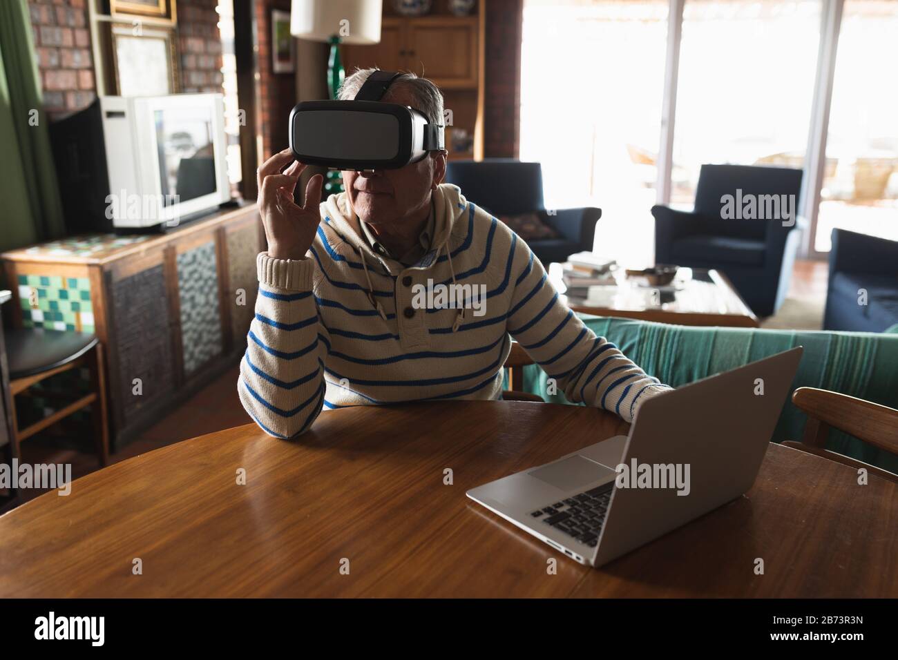 Senior man using virtual reality headset at home Stock Photo