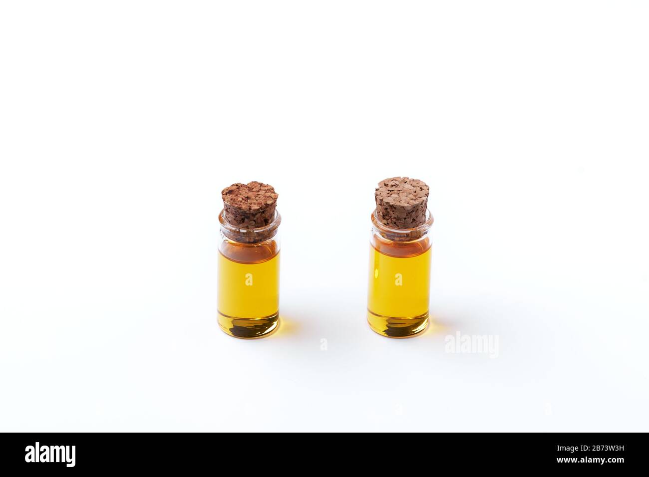 Two clear glass bottles with a cork with walnut oil (Juglans Regia) sample on a white background with copy space Stock Photo