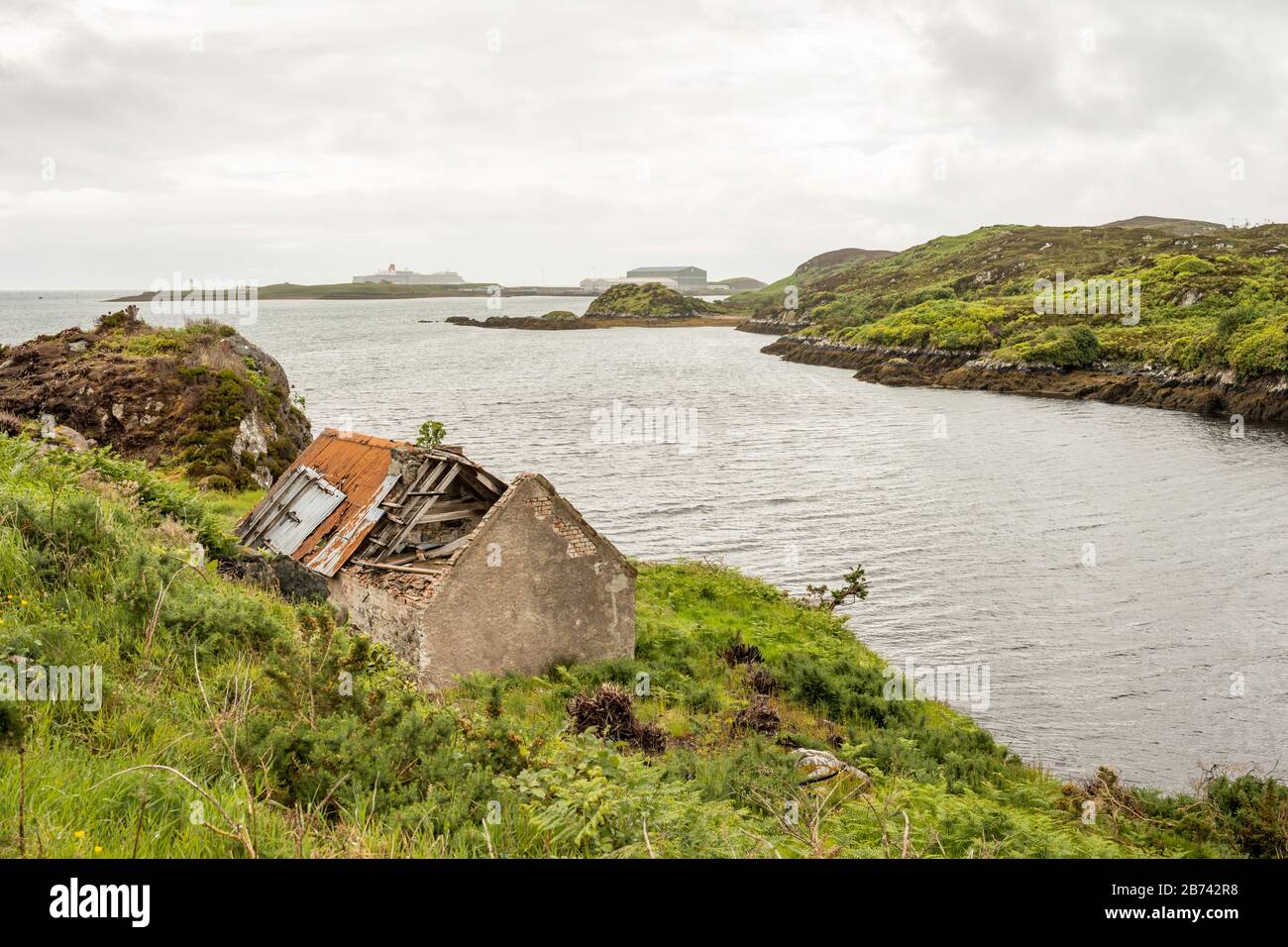 An abandoned cottage on the shore of Stornoway Bay, in the grounds of Lews Castle, Stornoway, Scotland, UK.  Cunard ship Queen Eliszabeth can be seen. Stock Photo